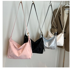 Detail view of large tote bags in pink, black, silver, and white with pleated texture