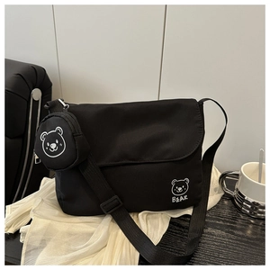 Detail of black nylon messenger bag with cute bear charm and adjustable shoulder strap