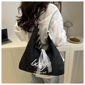 Close-up of black canvas hobo bag with white artistic lettering and lace bow detail