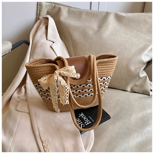 Detail of woven tote bag featuring a leather flap, large pearl accent and lace bow