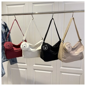 Detail of canvas messenger bags in four colors with matching bear-shaped coin purses