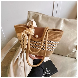 Close-up of woven straw tote bag with leather flap, large pearl and lace ribbon detail