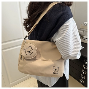 Detail of beige canvas messenger bag with cute bear print and matching coin purse