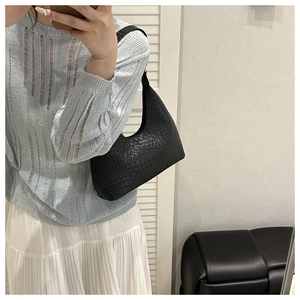 Mirror selfie showing a black woven crescent hobo bag for woman with textured details