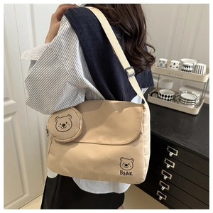 Close-up of beige canvas messenger bag with cartoon bear print and small round coin purse