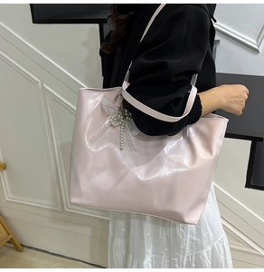 Detail of light pink tote bag featuring a white lace bow and elegant pearl pendant charm