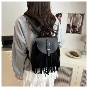 Detail view of black tassel backpack in matte leather and suede shown in a lifestyle setting