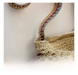 Detail of colorful woven shoulder strap and natural straw texture of the large tote bag