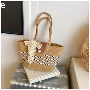 Detail of woven straw tote bag with brown leather flap, pearl clasp and lace bow accessory