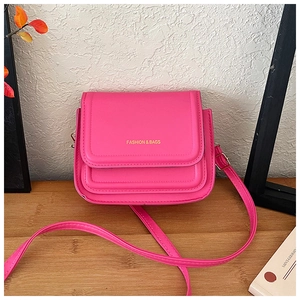 Détail du sac bandoulière fuchsia en cuir avec texte doré et fermoir sur bois naturel