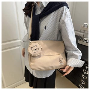Detail view of beige nylon messenger bag with bear graphic and matching coin purse