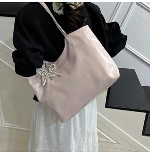 Pink glossy tote bag with pearl bow and lace detail shown on a shoulder strap