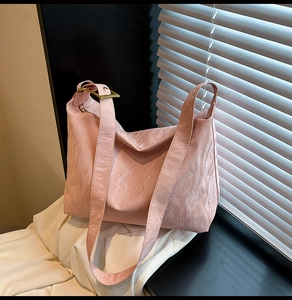 Detail of pink tote bag with pleated texture and gold metal buckle in sunlight