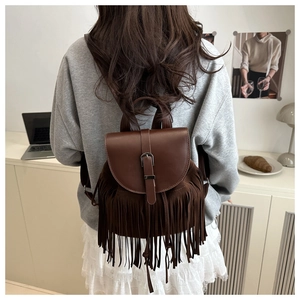 Detail view of a brown vintage tassel backpack featuring a leather flap and metal buckle