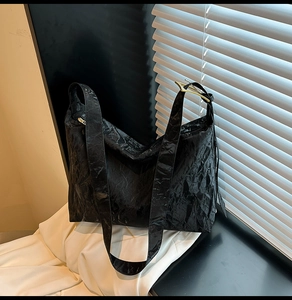 Close-up of black pleated texture shoulder bag with minimalist golden metal buckle detail
