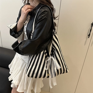 Fashionable black and white striped tote bag with white lace bow detail shown on a model