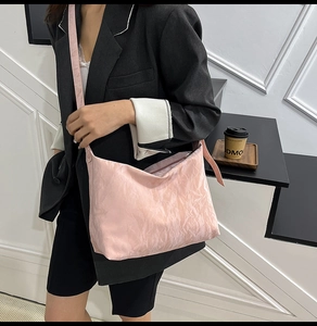 Close-up of pink pleated nylon shoulder bag worn by model in a minimalist urban studio
