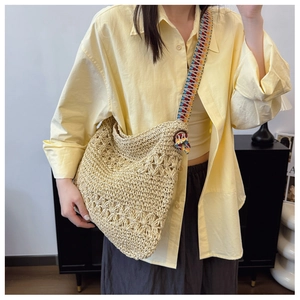 Detail of hollow straw tote bag featuring colorful ethnic wide woven shoulder strap