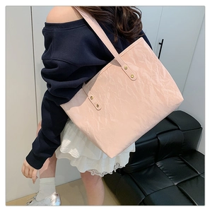 Pink tote bag detail with unique crinkled texture and metallic rivet shoulder strap