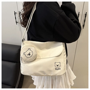 Detailed back view of cream canvas messenger bag with adjustable strap and bear coin purse