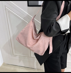 Close-up of the light pink textured tote bag showing wide shoulder strap and soft fabric