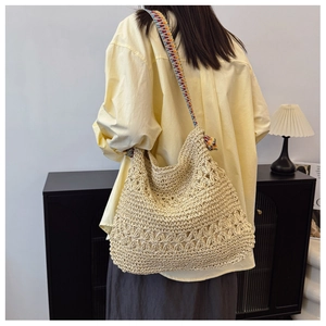 Detail of hand-woven straw tote bag with colorful ethnic embroidered shoulder strap