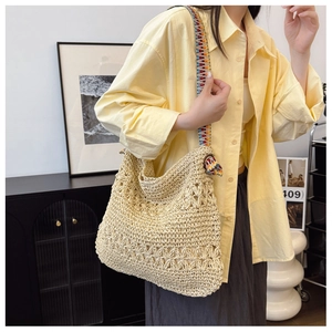 Detail of hand-woven straw tote bag with colorful ethnic patterned shoulder strap