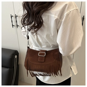 Détail du sac besace en daim marron avec franges élégantes et boucle en métal argenté