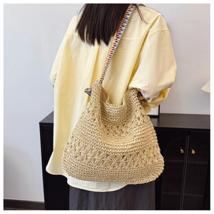 Detail of hand-woven straw tote with hollow-out pattern and ethnic woven shoulder strap