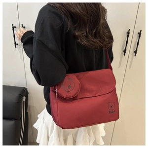 Close-up of red canvas messenger bag featuring a bear print and a small bear-shaped coin purse