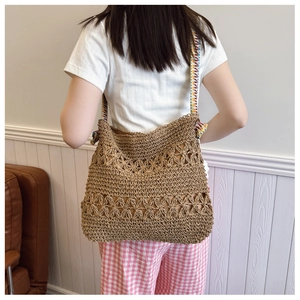 Close-up of a hollow woven straw tote bag featuring detailed crochet flower patterns