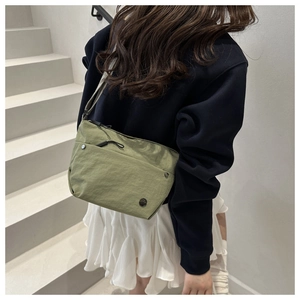 Model wearing a grass green nylon crossbody bag with zipper and front magnetic pocket