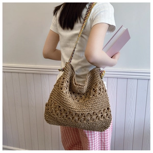 Detail of hollow floral crochet pattern on a large capacity straw tote bag with strap