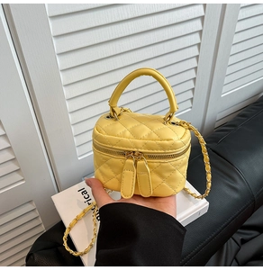 Dettaglio mini borsa a scatola gialla trapuntata con catena dorata e doppia zip
