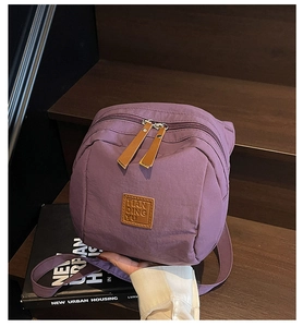 Détail d'un sac à dos violet en nylon avec fermetures en cuir brun sur des marches
