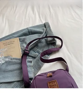 Détail de la bandoulière réglable et étiquette en cuir sur sac à bandoulière en nylon violet