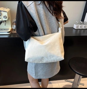 Detail of white large hobo bag with cloud pleat texture and matching wide strap