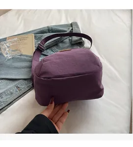 Gros plan d'un sac bandoulière en nylon violet avec sangle réglable et détail de logo