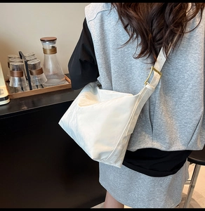 Detail of white nylon shoulder bag with shiny gold metal buckle and wide strap