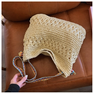 Close-up of beige crochet handbag with star patterns and colorful jacquard strap