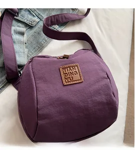Détail du sac bandoulière en nylon violet avec logo en cuir marron et sangle ajustable