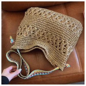 Detailed macro view of woven straw bag featuring hollow star crochet pattern and boho strap