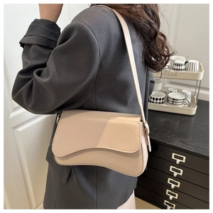 Close-up of cream underarm bag showing the unique asymmetrical curved flap and smooth texture