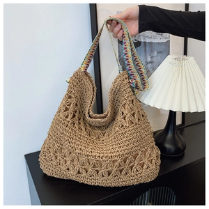Detail of hand-woven straw tote bag with floral patterns and a colorful geometric strap