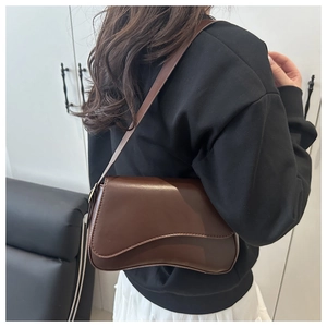 Brown asymmetric flap shoulder bag shown from back view on model for style and size