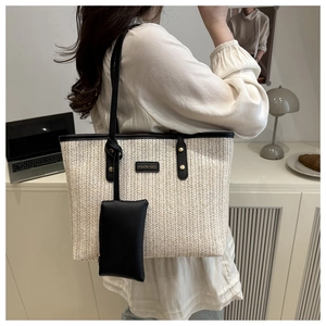 Dettaglio della borsa tote in paglia crema con manici in pelle nera e pochette