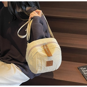 Vue détaillée d'un sac bandoulière en nylon beige avec double zip et tirettes cuir