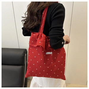 Macro detail of red floral tote bag featuring white flower patterns and ruffle edges