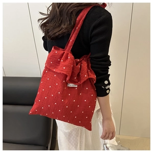 Shoulder shot of red mesh tote with white flower patterns and ruffle edge detail