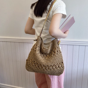 Minimalist straw tote bag with floral weave and colorful striped strap in a casual style